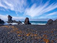 Schwarzer Kies und einzelne Lavaklippen